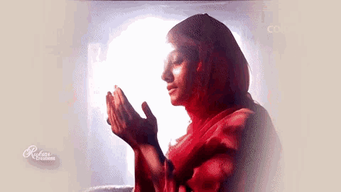 a woman in a red scarf is praying in front of a screen that says color