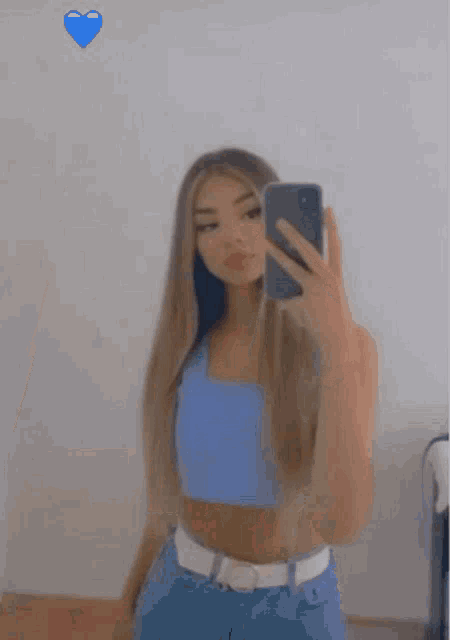 a girl is taking a selfie with her phone in a mirror .