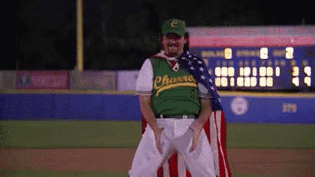 a man in a green phoenix jersey is holding an american flag on a baseball field