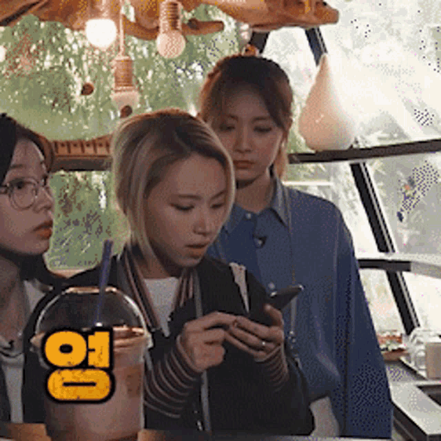 a group of young women are looking at their phones in a store