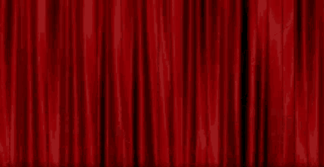 a spotlight shines on a stage with a red curtain behind it