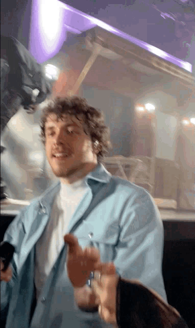 a man in a blue shirt is smiling and holding something in his hand