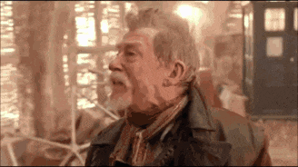 a man with a beard and a leather jacket is standing in front of a building .