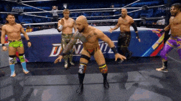 a group of wrestlers are standing in a wrestling ring with the word aew on the wall behind them