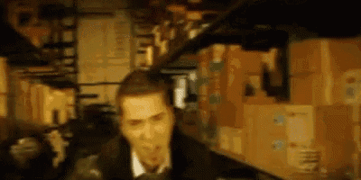 a man in a suit and tie is standing in a room filled with lots of boxes .