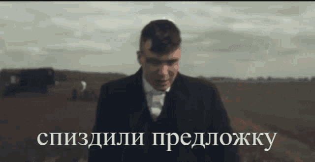 a man in a suit and tie is standing in a field with a caption in a foreign language that starts with the letter y