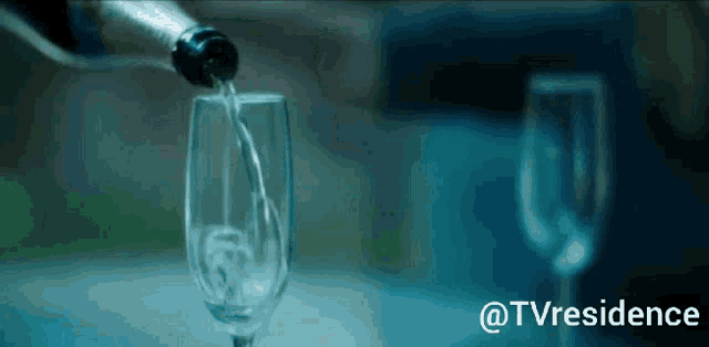 a bottle of champagne is being poured into a glass with @tvresidence written on the bottom