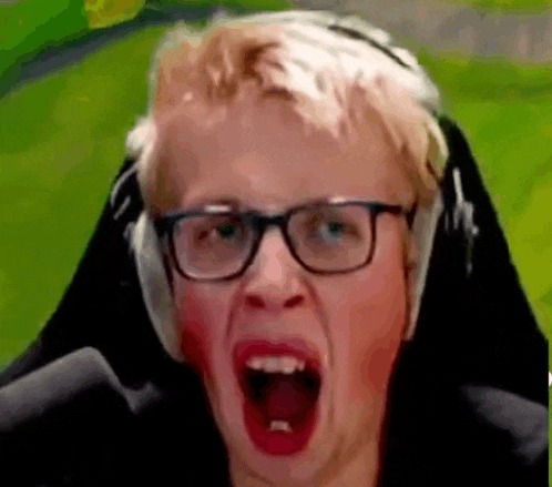 a man wearing glasses and headphones is making a funny face while playing a video game .