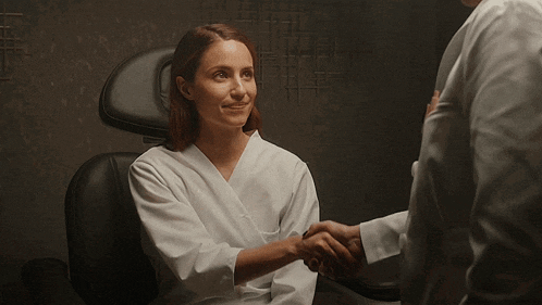 a woman in a white robe is shaking hands with a man