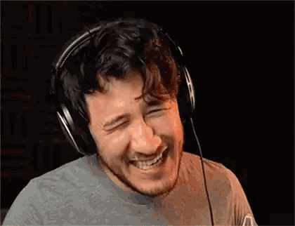 a man wearing headphones is laughing with his mouth open .