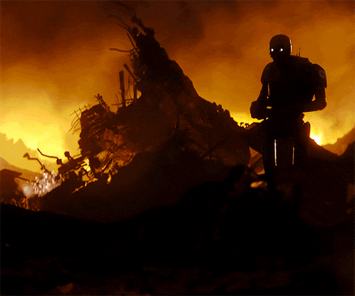 a silhouette of a man standing in front of a fire