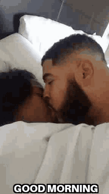 a man and a woman are kissing in bed with the words `` good morning '' written below them .
