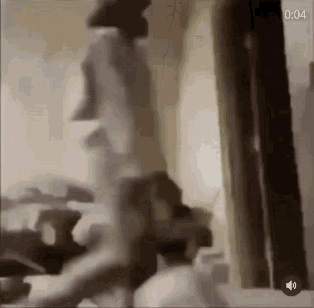 a blurred image of a person walking in a room with the time 4:04