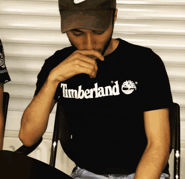 a man wearing a hat and a black timberland shirt