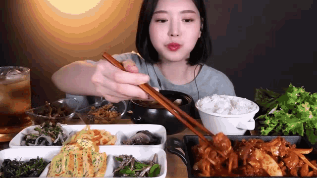a woman is eating a meal with chopsticks and rice