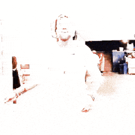 a man with a beard wearing a white shirt and a baseball cap is walking down a hallway