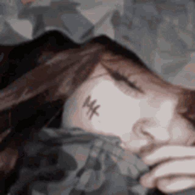 a woman with a tattoo on her face is sleeping in a bed .