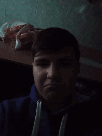 a young man in a blue sweatshirt looks down at something
