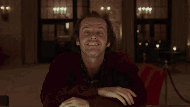 a man in a red sweater is smiling with his hands on his hips
