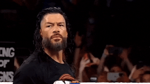 roman reigns is wearing a black shirt and has a beard .