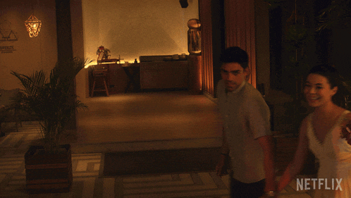 a man and a woman are walking in a room with a netflix logo on the bottom