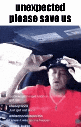 a man in a red shirt is sitting in the driver 's seat of a car with his hands on his head .