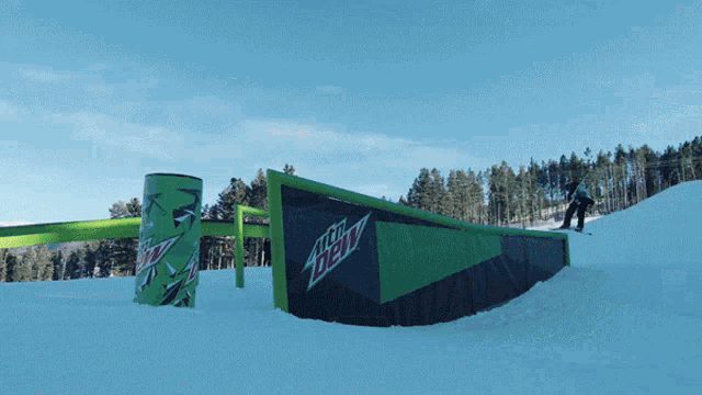 a snowboarder is doing a trick near a mtn dew advertisement