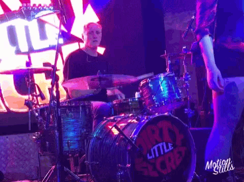 a man playing drums with a drum that says dirty little secret on it