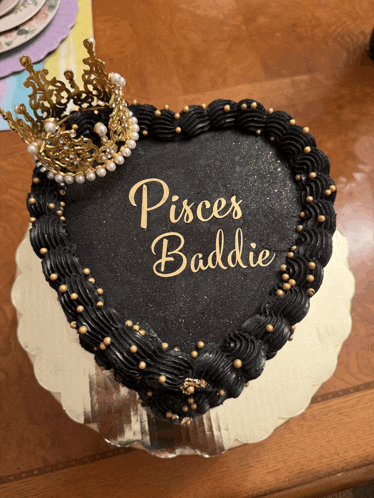 a black heart shaped cake with the words pisces baddie on it