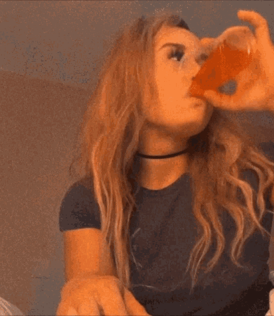 a woman in a black shirt is drinking from a small cup