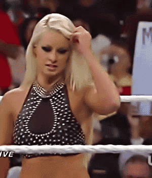 a woman in a polka dot top is standing in a wrestling ring .