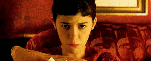 a young woman is sitting on a red couch holding a piece of paper in her hand .