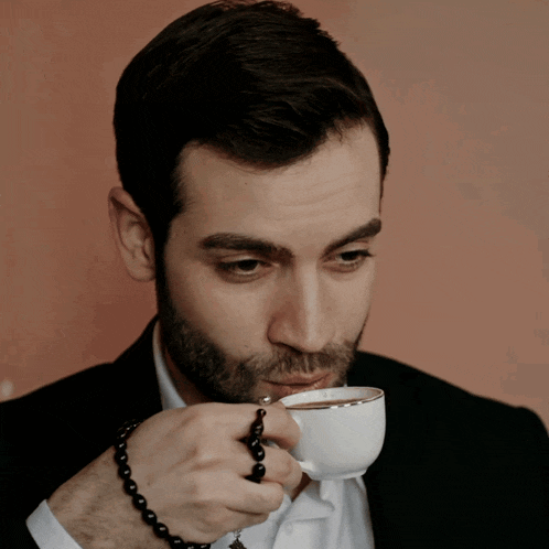 a man with a beard is drinking from a cup