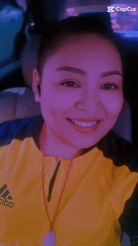 a woman in a yellow adidas jacket is smiling