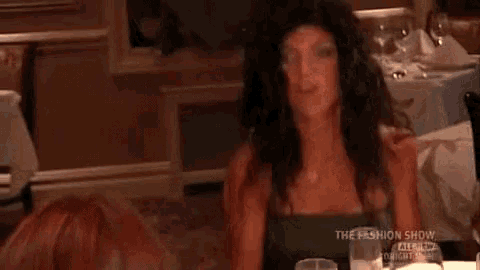 a woman is sitting at a table in a restaurant with her hair in her hand .