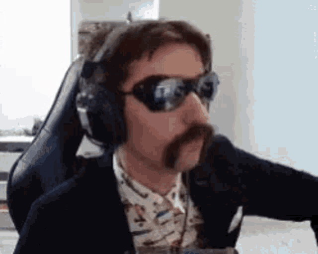 a man with a mustache and headphones is sitting in a chair .