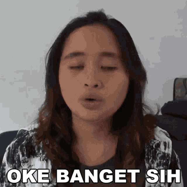 a woman is making a funny face with the words oke banget sih written below her