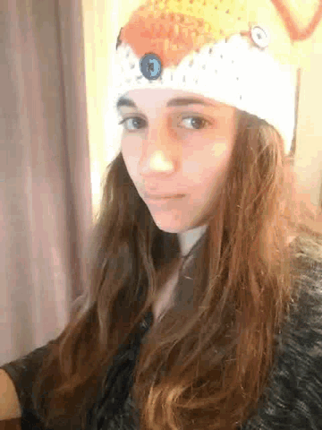 a woman with long hair is wearing a knitted hat with a fish on it .