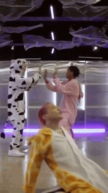 a man in a cow costume is standing next to another man in a giraffe costume in a dance studio .
