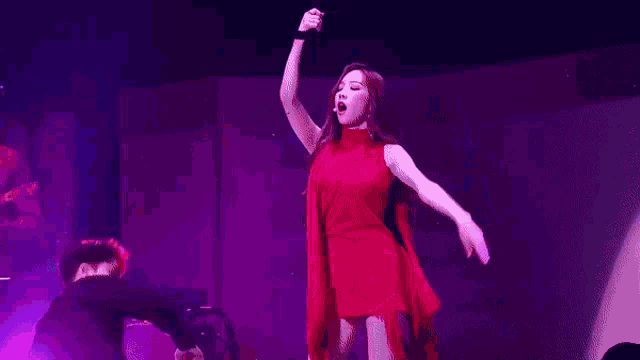 a woman in a red dress is dancing on a stage while a man falls on the floor