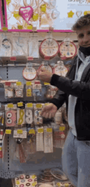 a man stands in front of a display of party supplies including balloons and masks