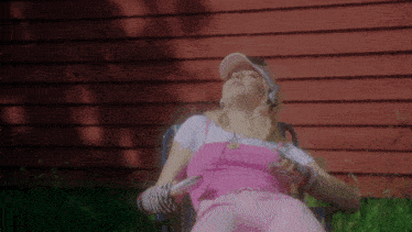 a woman wearing headphones and a pink hat sits in a chair