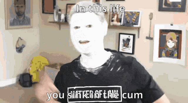a man with a white face and a black shirt that says in this life
