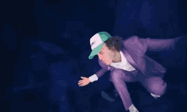 a man wearing a purple suit and a white hat that says ' witchcraft '