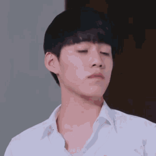 a close up of a young man wearing a white shirt making a funny face .
