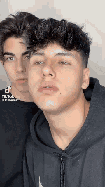 two young men are standing next to each other and one of them is wearing a black hoodie with the word air jordan on it .
