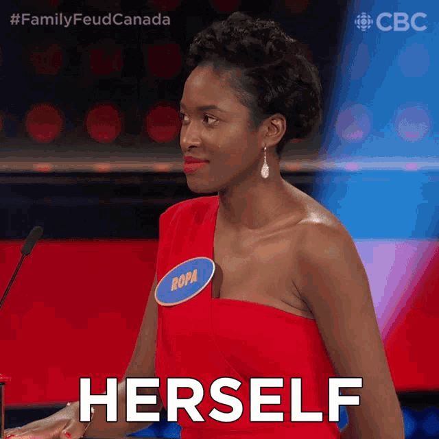 a woman in a red dress with a name tag that says ropa stands in front of a microphone and says herself