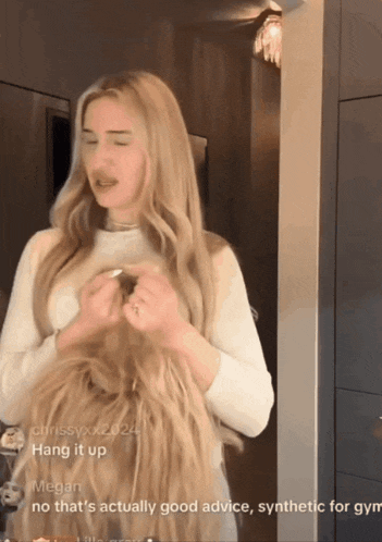 a woman with very long blonde hair is standing in front of a mirror with the caption hang it up