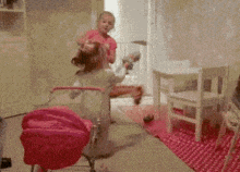 a girl in a pink shirt is playing with a toy stroller