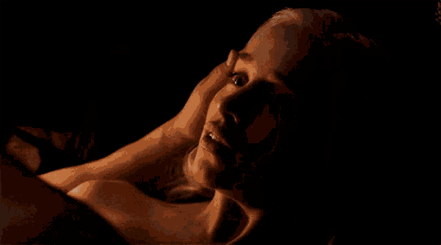 a woman is laying on a man 's lap in the dark .